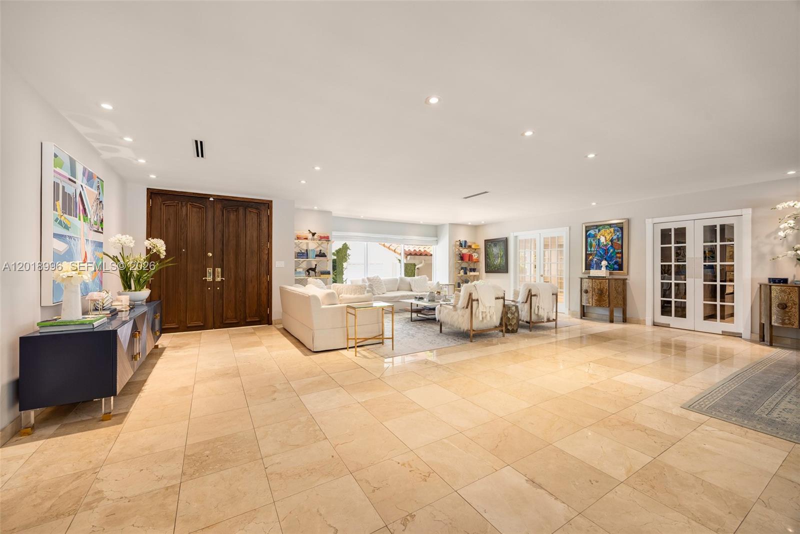 A spacious living room features light tile flooring, white furniture, and a dark wood door — 7230 Vistalmar St, Coral Gables FL 33143, CORAL GABLES, FL