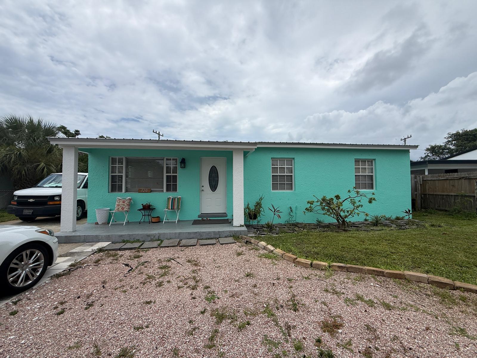 A single-story turquoise house with a front porch, gravel driveway, and a white front door — 320 W 29th Street, Riviera Beach FL 33404, RIVIERA BEACH, FL