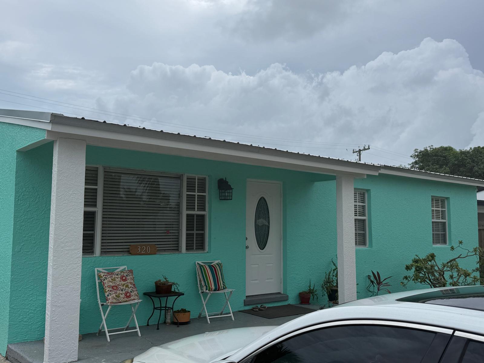 A teal house with a white front door and porch sits under a cloudy sky — 320 W 29th Street, Riviera Beach FL 33404, RIVIERA BEACH, FL