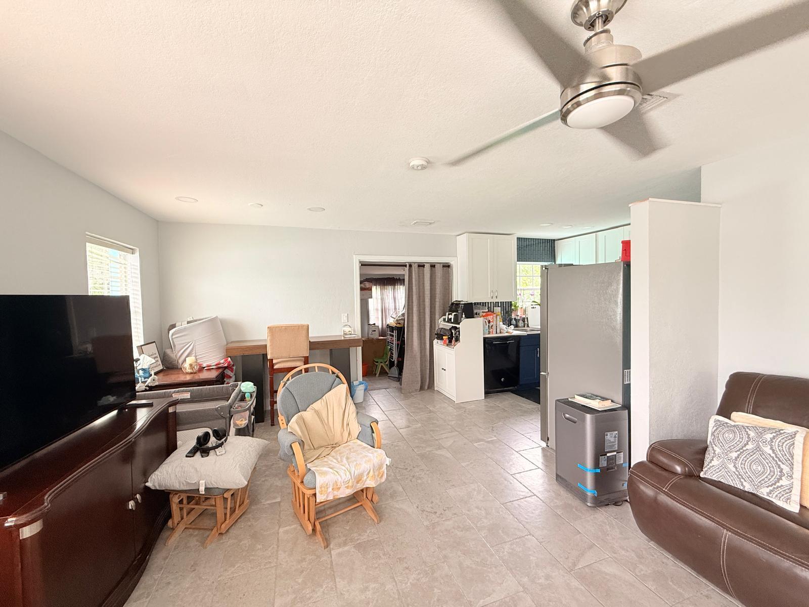 A living room with tile flooring, a ceiling fan, and an open view into the kitchen — 320 W 29th Street, Riviera Beach FL 33404, RIVIERA BEACH, FL