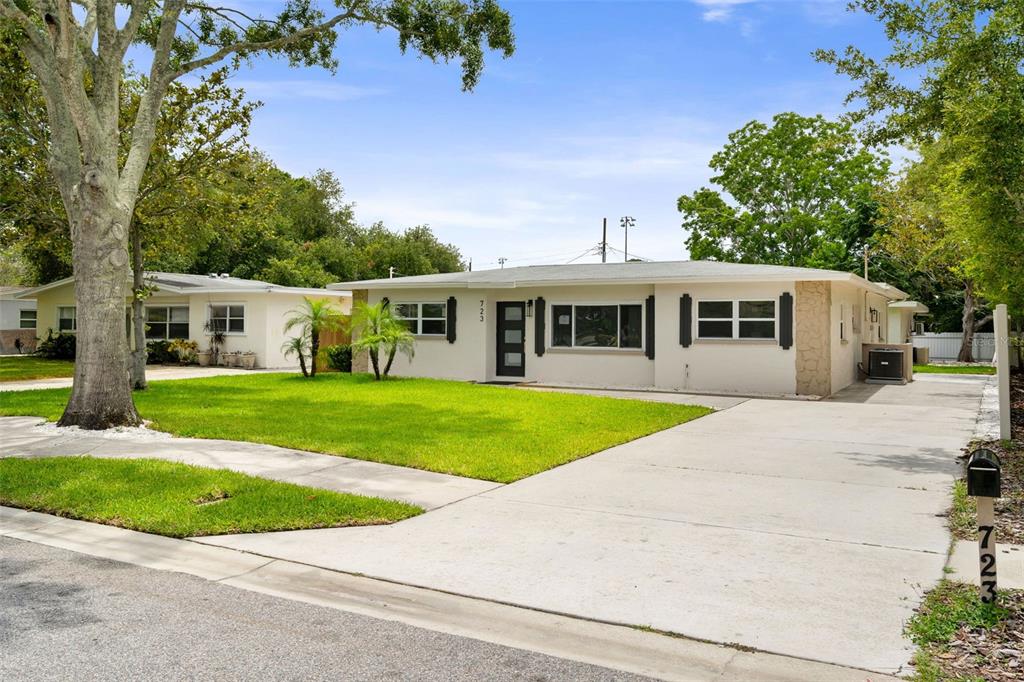 A single-story house with a white exterior, a concrete driveway, and a green lawn — 723 W BAYSHORE DRIVE, TARPON SPRINGS, FL