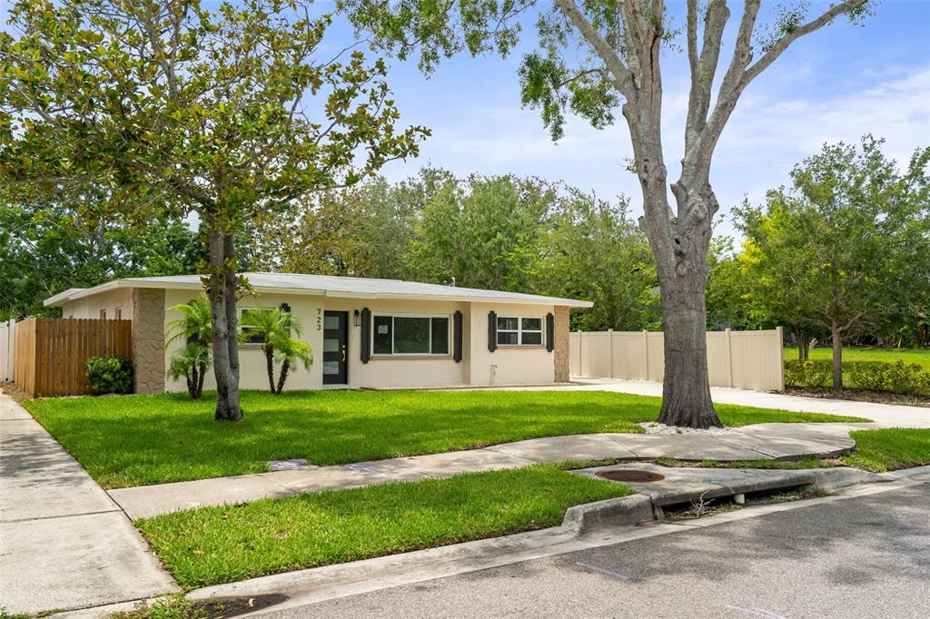A single-story house with a light-colored exterior, a front lawn, and mature trees — 723 W BAYSHORE DRIVE, TARPON SPRINGS, FL