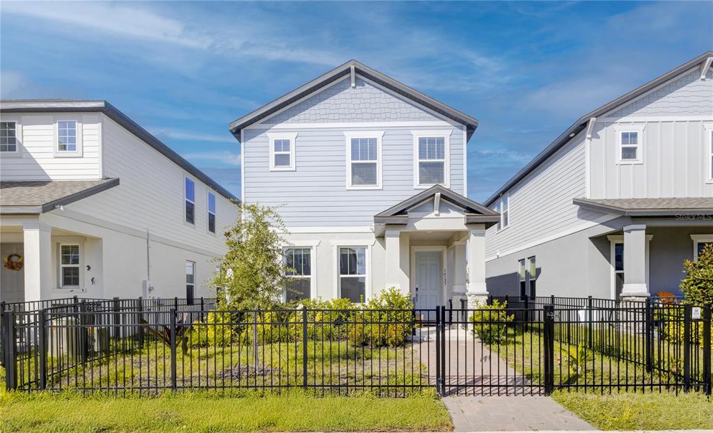 A two-story light blue house with a front porch and black metal fence — 14123 FRASIER STREET, WINTER GARDEN, FL