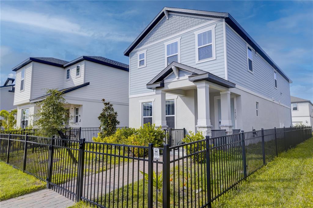 A two-story house with light blue siding and a black metal fence in the yard — 14123 FRASIER STREET, WINTER GARDEN, FL