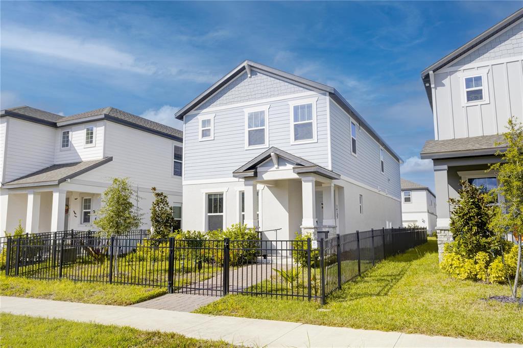 A light blue two-story house with a fenced front yard and a paved walkway — 14123 FRASIER STREET, WINTER GARDEN, FL
