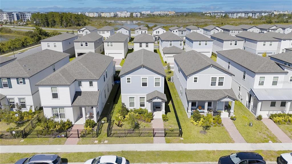 An aerial view shows three suburban houses with gray roofs and fenced front yards — 14123 FRASIER STREET, WINTER GARDEN, FL