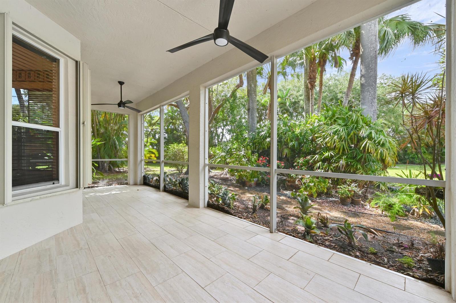 A screened-in patio features light-colored tile flooring, two ceiling fans, and views of lush landscaping — 6439 Pebble Creek Way, Boynton Beach FL 33437, BOYNTON BEACH, FL
