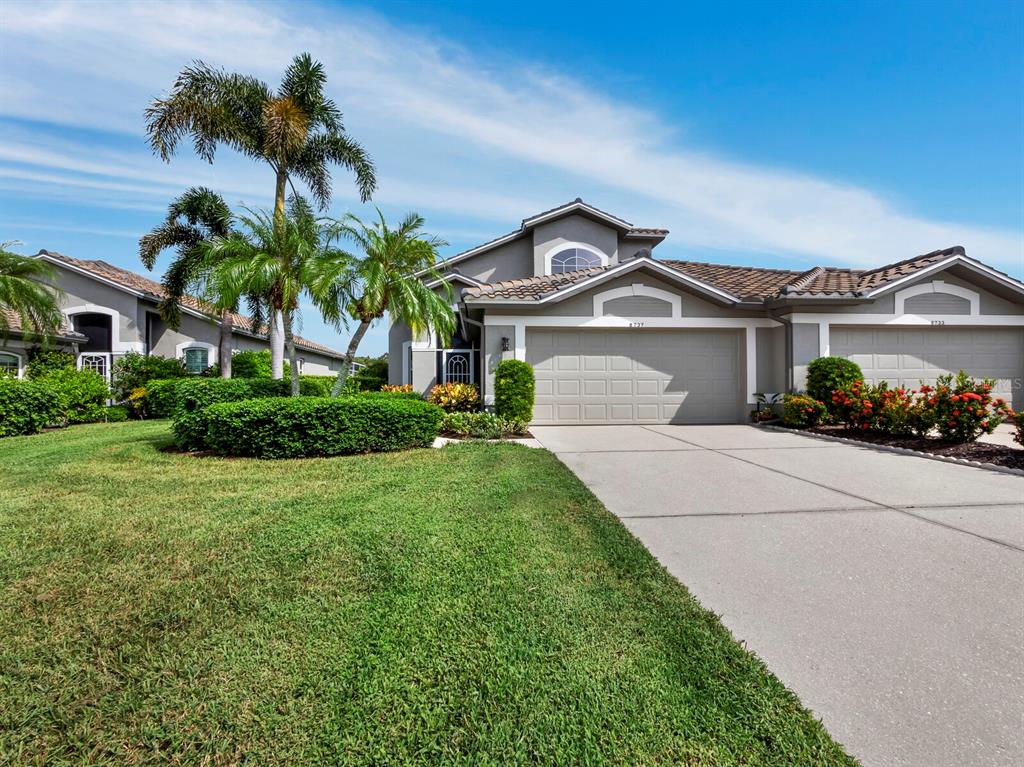 A single-story suburban house with a gray exterior, a two-car garage, and palm trees — 8737 PEBBLE CREEK LANE, SARASOTA, FL