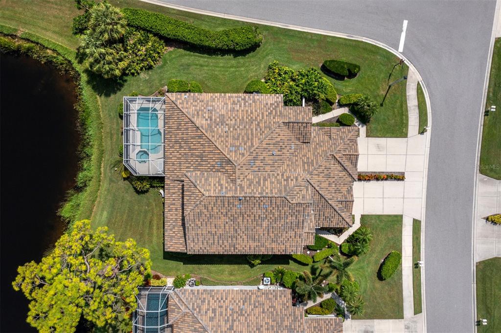 An aerial view shows a house with a tiled roof, a pool cage, and landscaping — 8737 PEBBLE CREEK LANE, SARASOTA, FL