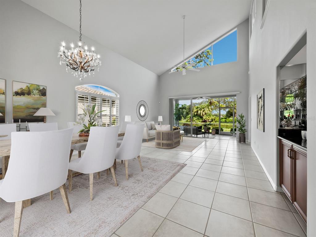A dining room and living area feature vaulted ceilings, tile floors, and large glass doors — 8737 PEBBLE CREEK LANE, SARASOTA, FL
