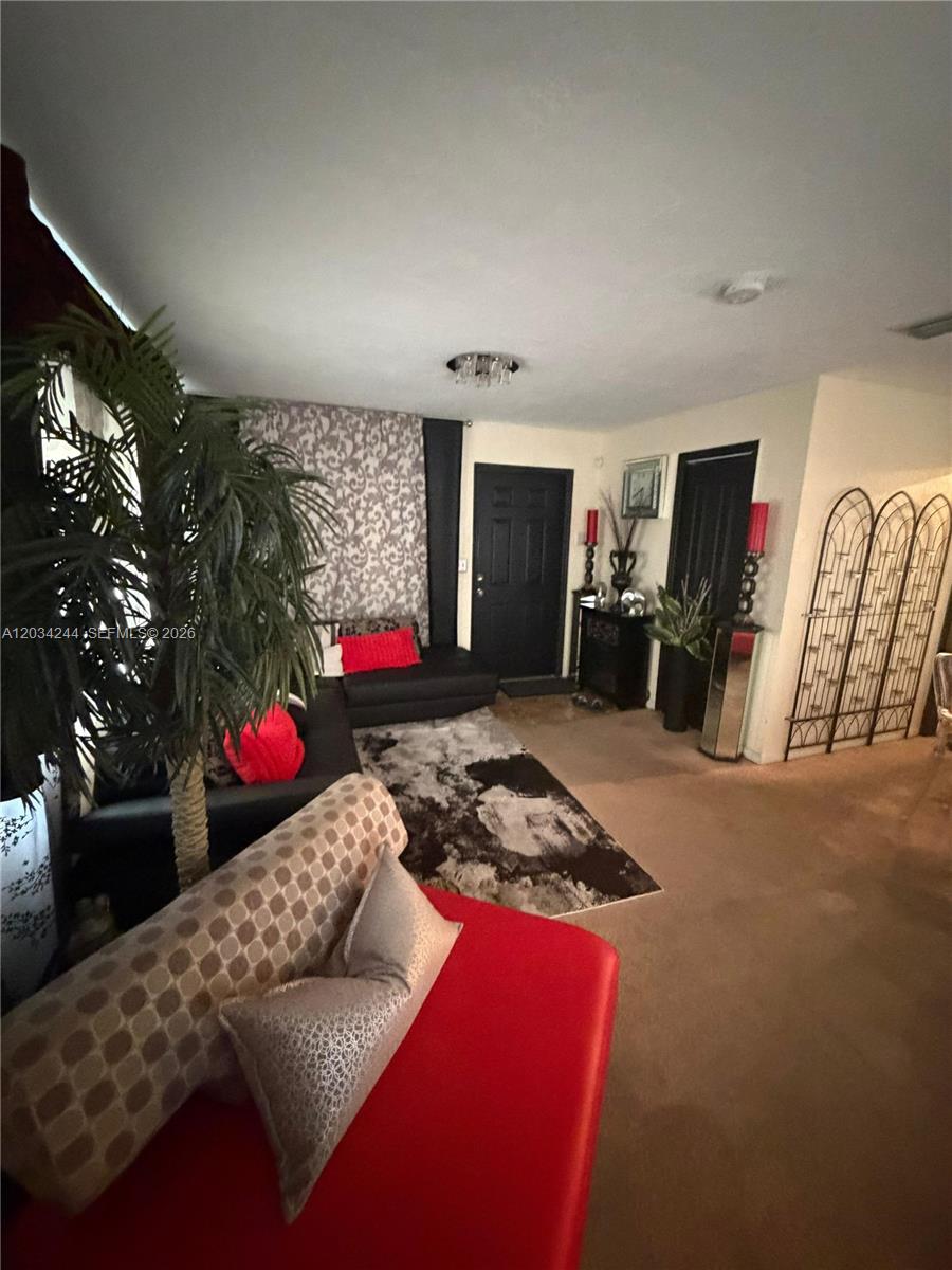 A living room features black sofas, a patterned area rug, and a decorative metal screen — 16980 SW 104th Ave, Miami FL 33157, MIAMI, FL