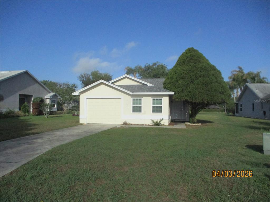 A single-story house with a light yellow exterior, a one-car garage, and a large tree — 6357 EGRET DRIVE, LAKELAND, FL