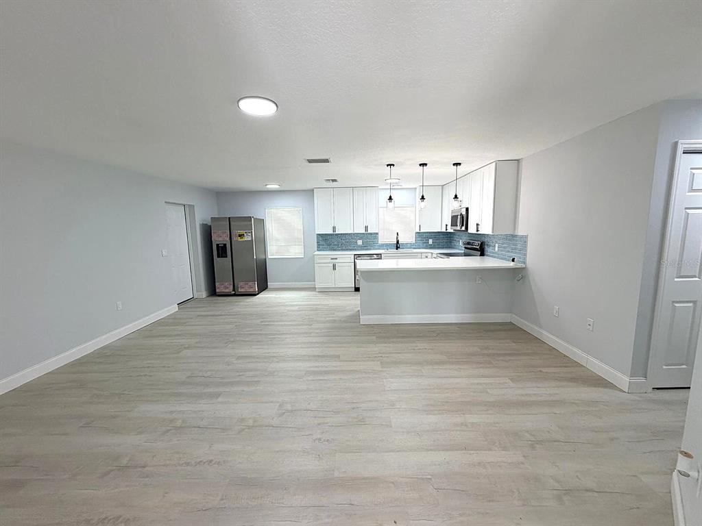 A kitchen with white cabinets, a breakfast bar, and light wood-look flooring — 445 NW 10TH AVENUE, WEBSTER, FL