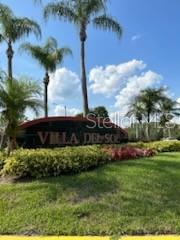 A curved sign for Villa Del Sol stands in a landscaped area with palm trees — 2210 GRAND CAYMAN COURT UNIT 1735, KISSIMMEE, FL