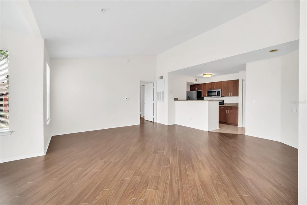 An open-concept living area features wood-look flooring and a kitchen with dark wood cabinets — 2210 GRAND CAYMAN COURT UNIT 1735, KISSIMMEE, FL