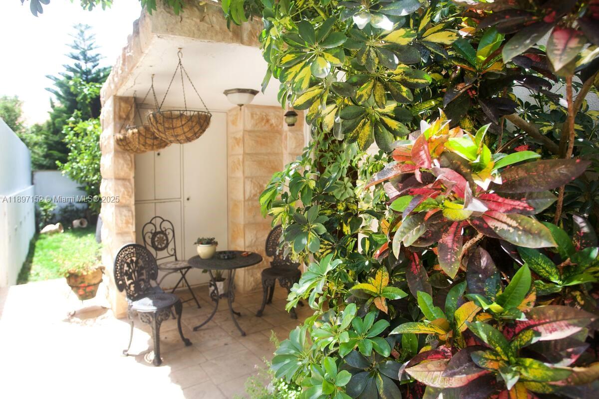 A small patio features a stone wall, wrought iron furniture, and lush surrounding foliage — Hapiyyus 10, IL 4681400, IL