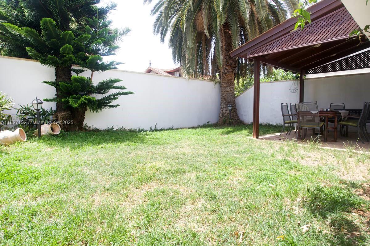 A grassy backyard features a covered patio with dining furniture and a large palm tree — Hapiyyus 10, IL 4681400, IL