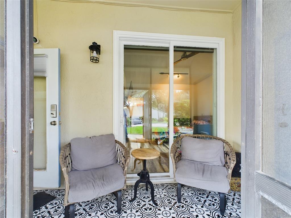 A covered patio features two wicker chairs, a small round table, and patterned floor tiles — 2049 SAN MARCOS DRIVE SE UNIT 127, WINTER HAVEN, FL