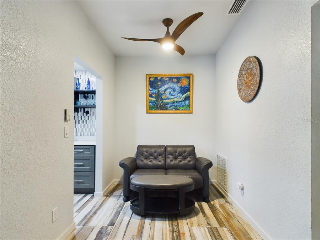 A small seating area features a dark loveseat, a round coffee table, and wood-look flooring — 2049 SAN MARCOS DRIVE SE UNIT 127, WINTER HAVEN, FL
