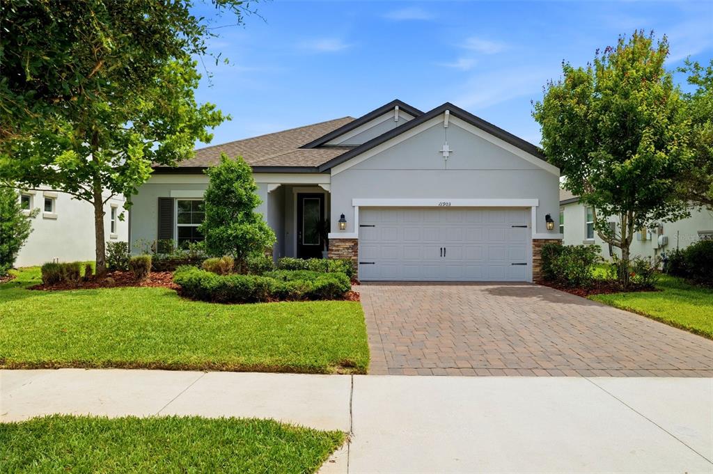 A single-story house with a gray stucco exterior, stone accents, and a paved driveway — 11903 RANCHERS GAP DRIVE, ODESSA, FL
