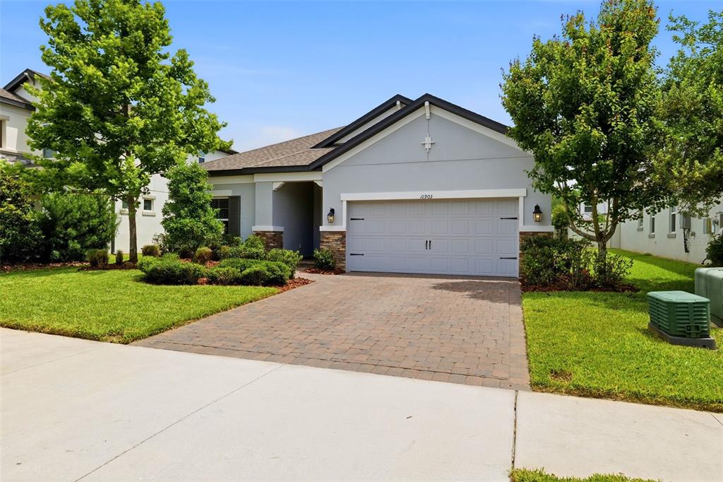 A single-story house with a gray garage, stone accents, and a paved driveway — 11903 RANCHERS GAP DRIVE, ODESSA, FL