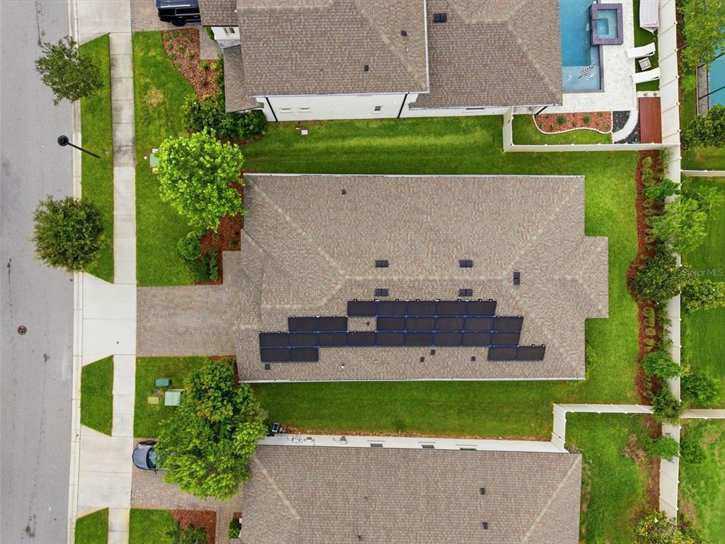 An aerial view shows a house with solar panels on its roof and a backyard — 11903 RANCHERS GAP DRIVE, ODESSA, FL