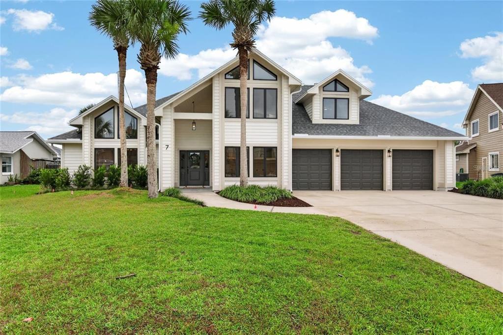 A two-story house with a white exterior, three garage doors, and two palm trees — 7 CHINOOK COURT, PALM COAST, FL