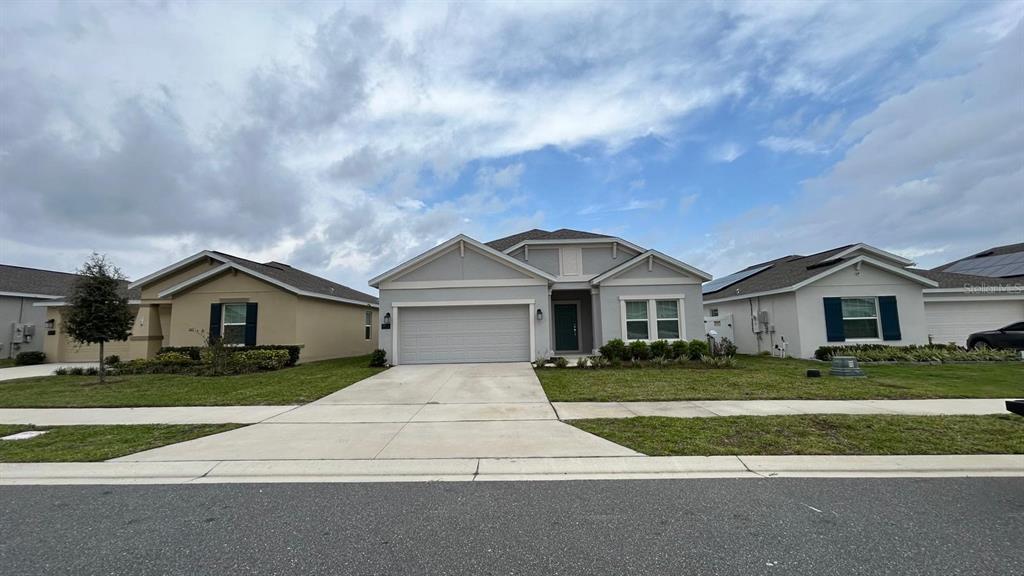 A street-level view of a light gray single-story house with a two-car garage — 913 LAUREL VIEW WAY, GROVELAND, FL