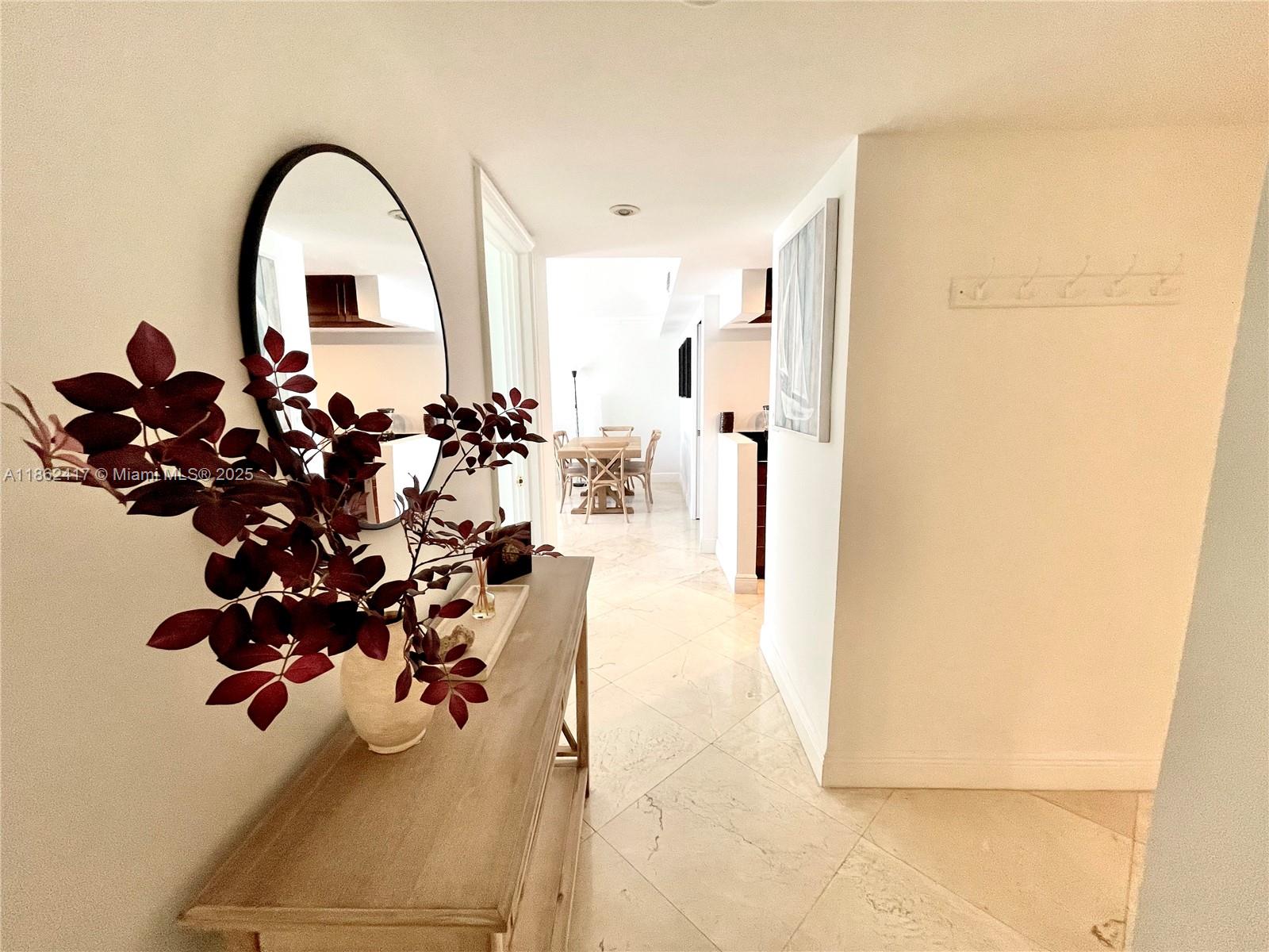 A hallway with light tile flooring leads to a dining area with a wooden table — 177 Ocean Lane Dr # 209, Key Biscayne FL 33149, KEY BISCAYNE, FL
