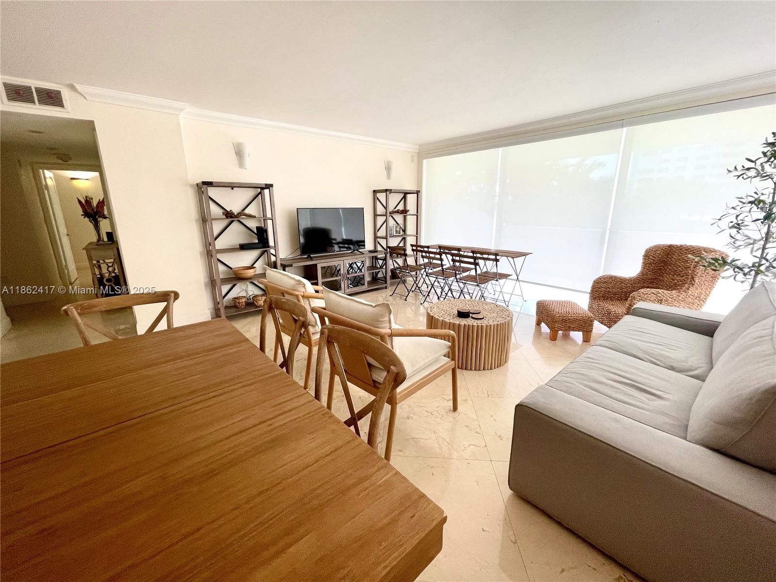 A living room with light tile floors, a grey sofa, and a dining area — 177 Ocean Lane Dr # 209, Key Biscayne FL 33149, KEY BISCAYNE, FL