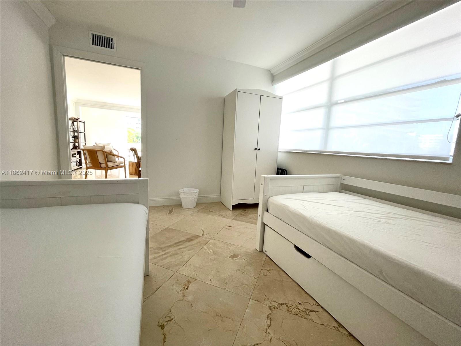 A bedroom features two white beds, a wardrobe, and light-colored tile flooring — 177 Ocean Lane Dr # 209, Key Biscayne FL 33149, KEY BISCAYNE, FL