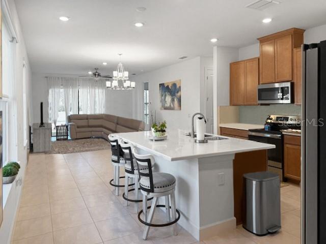 A kitchen with a white island and bar stools opens into a living area — 1305 LOMBARDI COURT, KISSIMMEE, FL