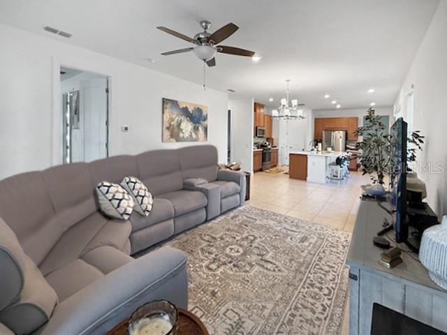 A living room with a gray sectional sofa, area rug, and an open kitchen beyond — 1305 LOMBARDI COURT, KISSIMMEE, FL