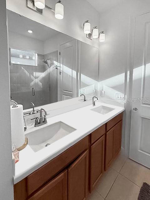 A bathroom features a double vanity with wood cabinets, white countertops, and a large mirror — 1305 LOMBARDI COURT, KISSIMMEE, FL