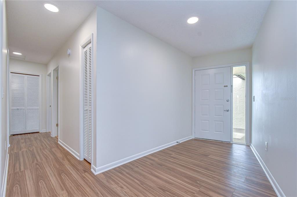 An entryway with wood-look flooring, white walls, recessed lighting, and a white front door — 16131 GARDENDALE DRIVE, TAMPA, FL