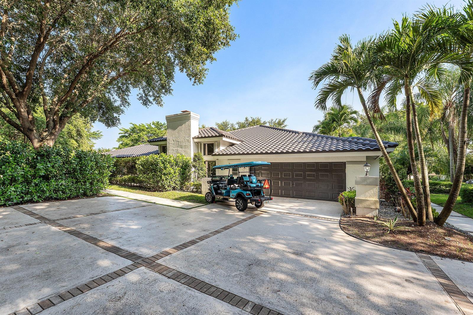 A single-story house with a tiled roof, a two-car garage, and a golf cart parked outside — 7210 W Cypresshead Drive, Parkland FL 33067, PARKLAND, FL