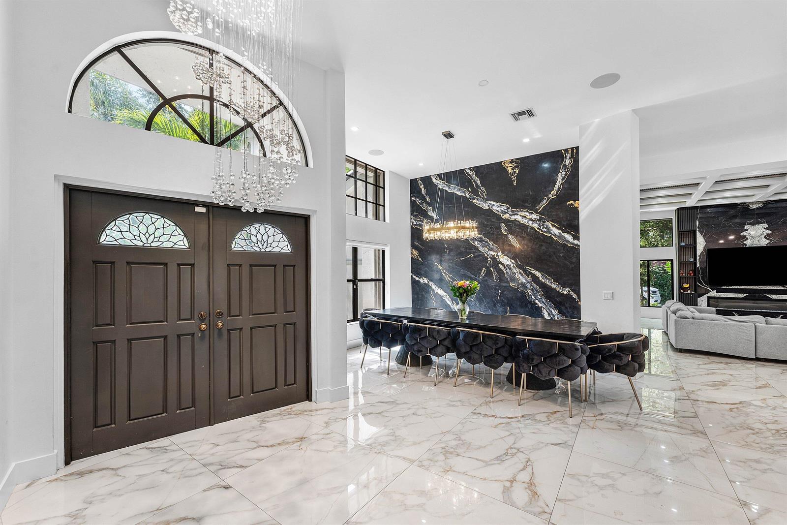 A dining area features a black marble accent wall, crystal chandelier, and white marble flooring — 7210 W Cypresshead Drive, Parkland FL 33067, PARKLAND, FL