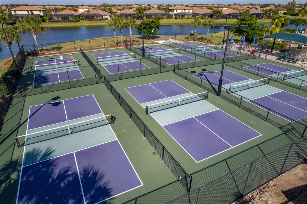 An aerial view shows multiple pickleball courts with purple and light blue surfaces — 8205 GRAND ESTUARY TRAIL UNIT 404, BRADENTON, FL