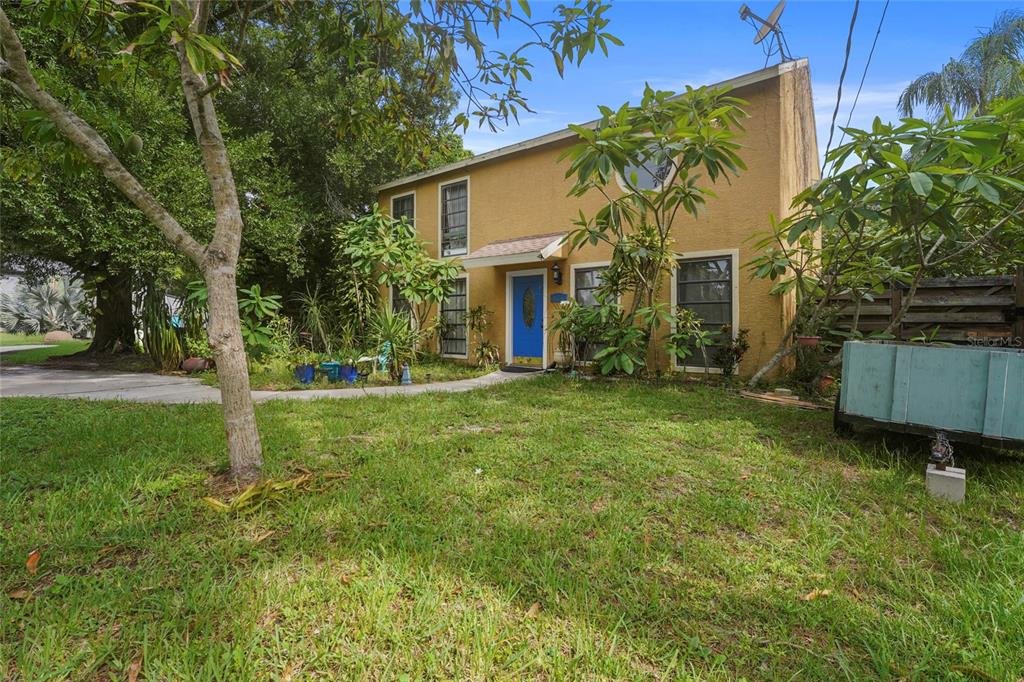 A two-story yellow house with a blue front door sits behind a grassy front yard — 3153 MAIDEN LANE, SARASOTA, FL