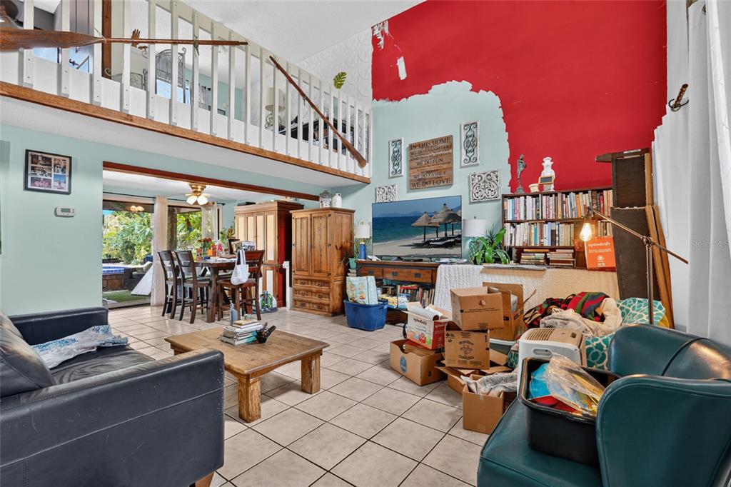 A living room with a loft, tiled floors, and a partially painted red accent wall — 3153 MAIDEN LANE, SARASOTA, FL
