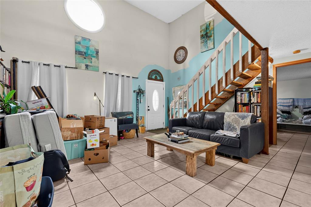 A living room with tile floors, a vaulted ceiling, a staircase, and scattered moving boxes — 3153 MAIDEN LANE, SARASOTA, FL