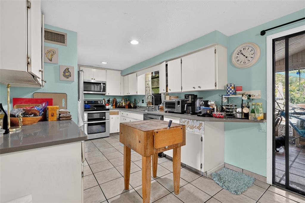 A kitchen with white cabinets, light blue walls, tile flooring, and a wooden butcher block island — 3153 MAIDEN LANE, SARASOTA, FL