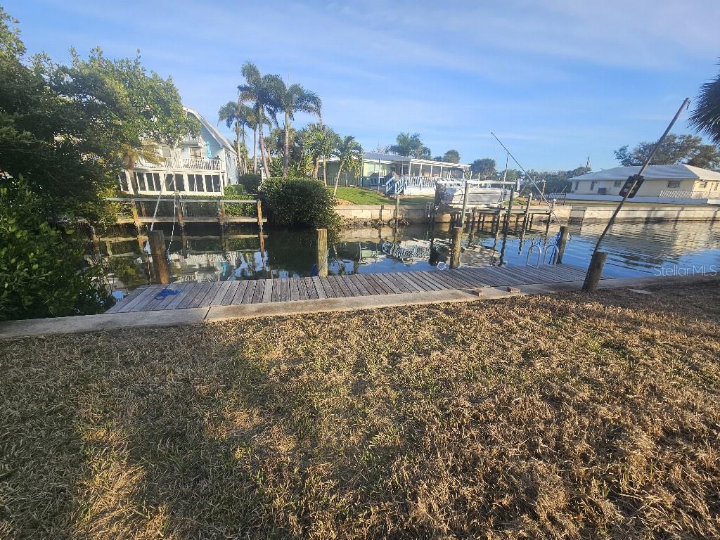 A wooden dock extends over a canal toward houses and palm trees under a blue sky — 251 WINSON AVENUE, ENGLEWOOD, FL