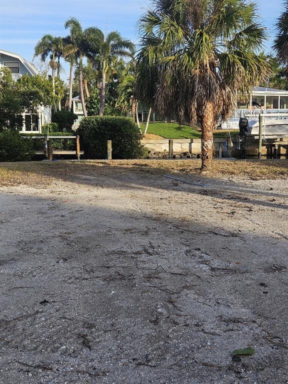 A vacant, shell-covered waterfront lot features a palm tree and a wooden boat dock — 251 WINSON AVENUE, ENGLEWOOD, FL