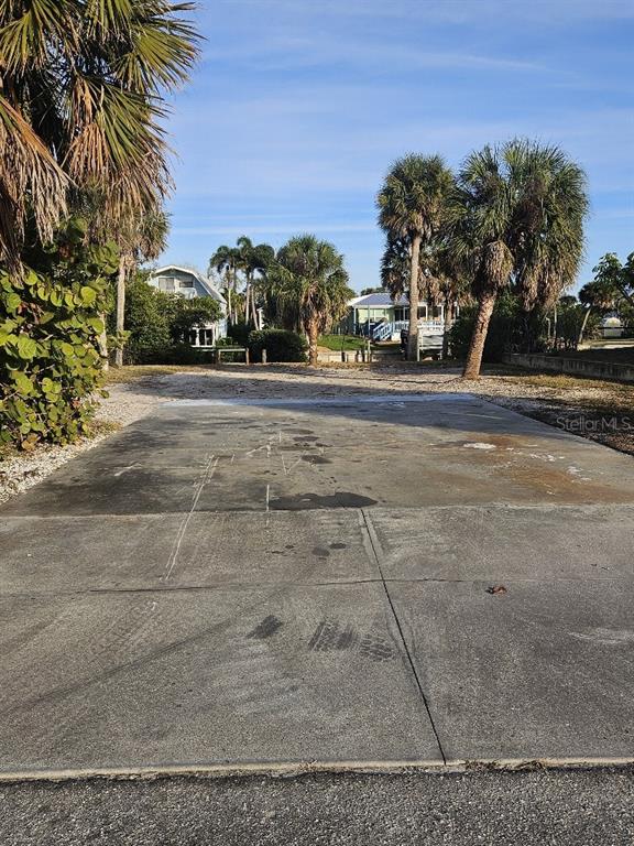 A concrete driveway leads to a vacant lot surrounded by palm trees and nearby houses — 251 WINSON AVENUE, ENGLEWOOD, FL