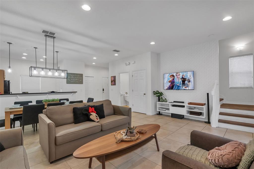 A living room with a sofa, coffee table, and wall-mounted television above a white console — 3023 RED GINGER ROAD, KISSIMMEE, FL