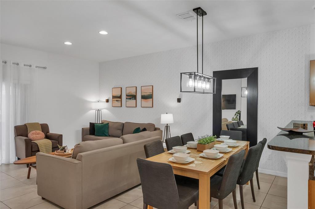 An open-concept living and dining area features a neutral sofa, dining table, and wall mirror — 3023 RED GINGER ROAD, KISSIMMEE, FL
