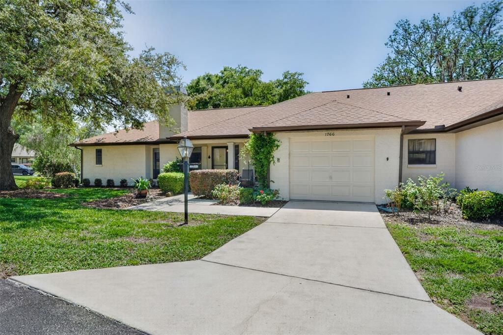 A single-story house with a beige stucco exterior, a brown shingled roof, and a concrete driveway — 1766 N ENSIGN POINT, CRYSTAL RIVER, FL