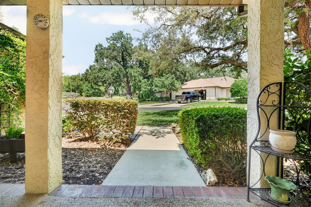 A view from a covered porch looking out toward a sidewalk, lawn, and neighboring house — 1766 N ENSIGN POINT, CRYSTAL RIVER, FL