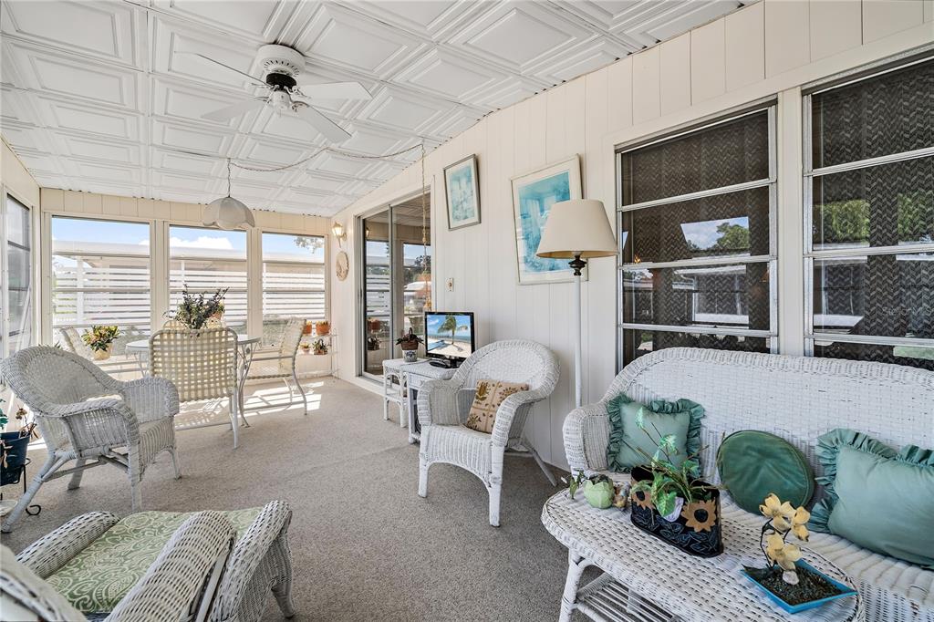 A sunroom features white wicker furniture, a patterned ceiling, and large windows overlooking the exterior — 3410 SPANISH OAK TERRACE, SARASOTA, FL